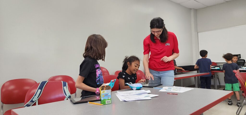Finch robotics class, teacher, and two students working on an assignment